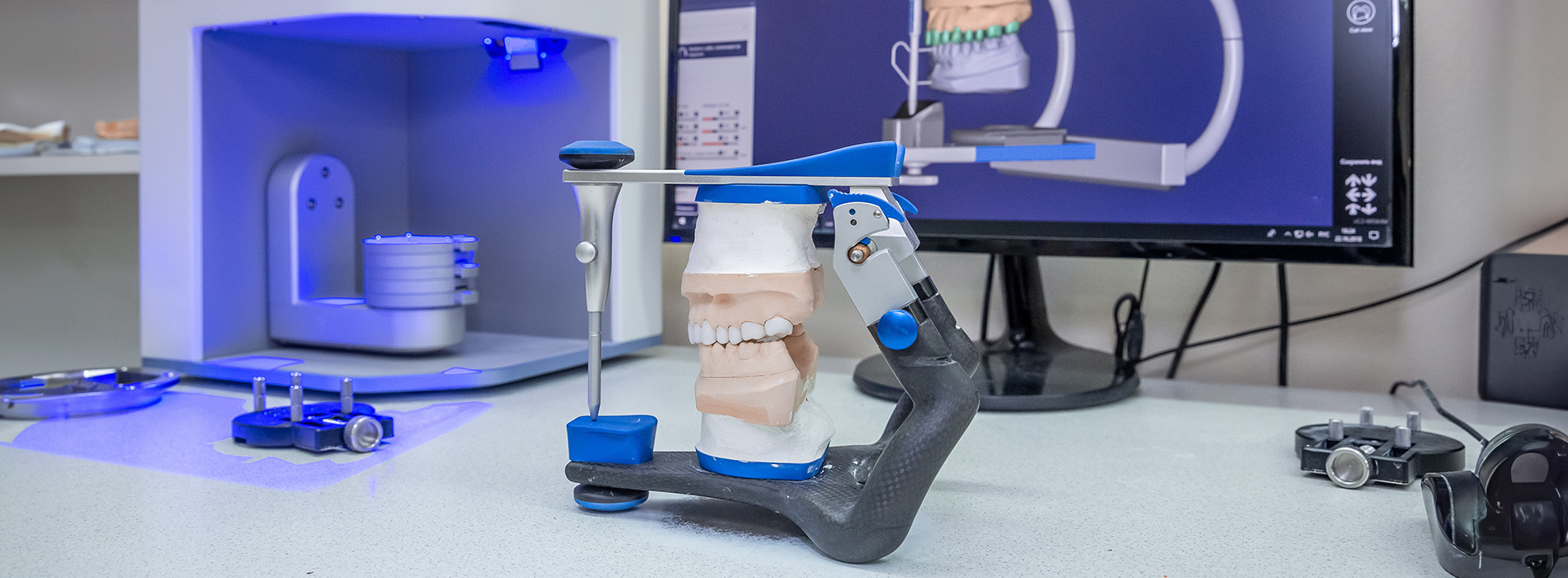 The image shows a computer monitor with blue lighting and various objects in a room, including a skeleton model and medical equipment.