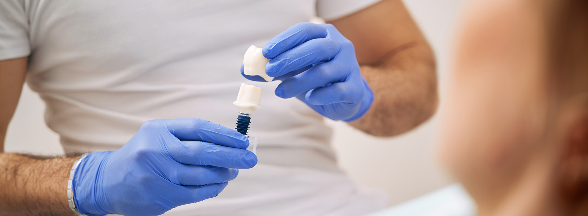 A man in a white shirt holding a blue test tube while wearing blue gloves.