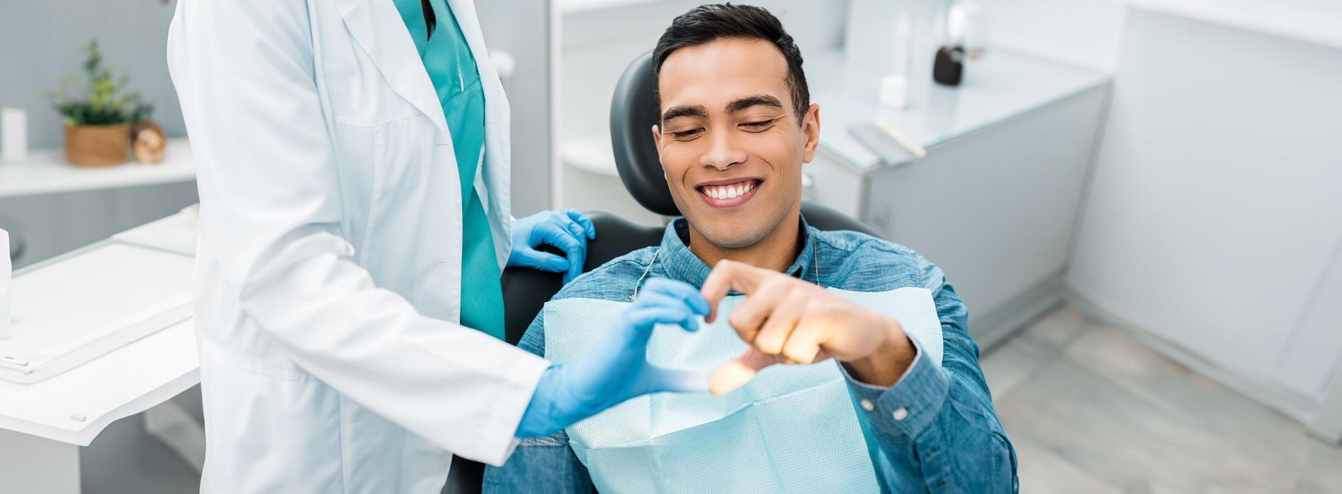 The image shows a group of people, possibly professionals given their attire and the setting that appears to be an office or professional environment. They are gathered around a table with a laptop on it, engaged in what seems to be a discussion or meeting.