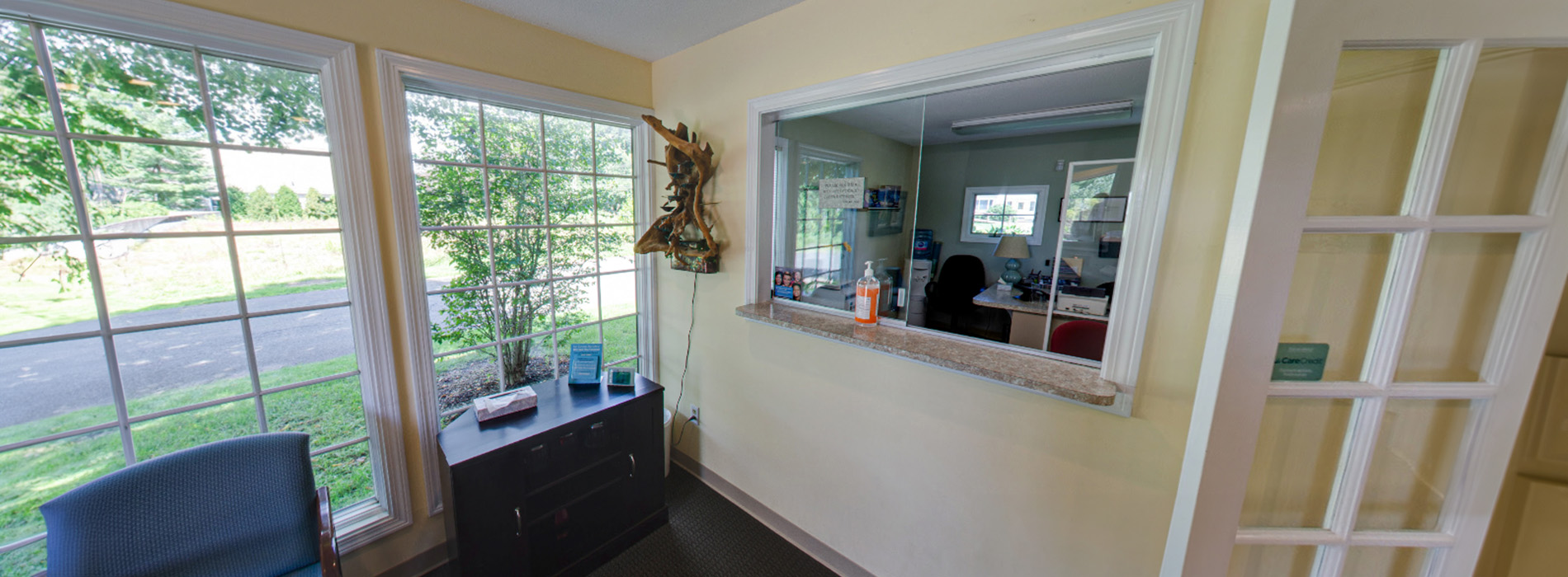 The image shows an interior space with a room featuring a large window, a countertop with a few items on it, and a view of another room through the window.