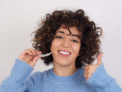 The image shows a person with curly hair and a blue sweater, smiling and giving a thumbs-up gesture, with two different expressions side by side.