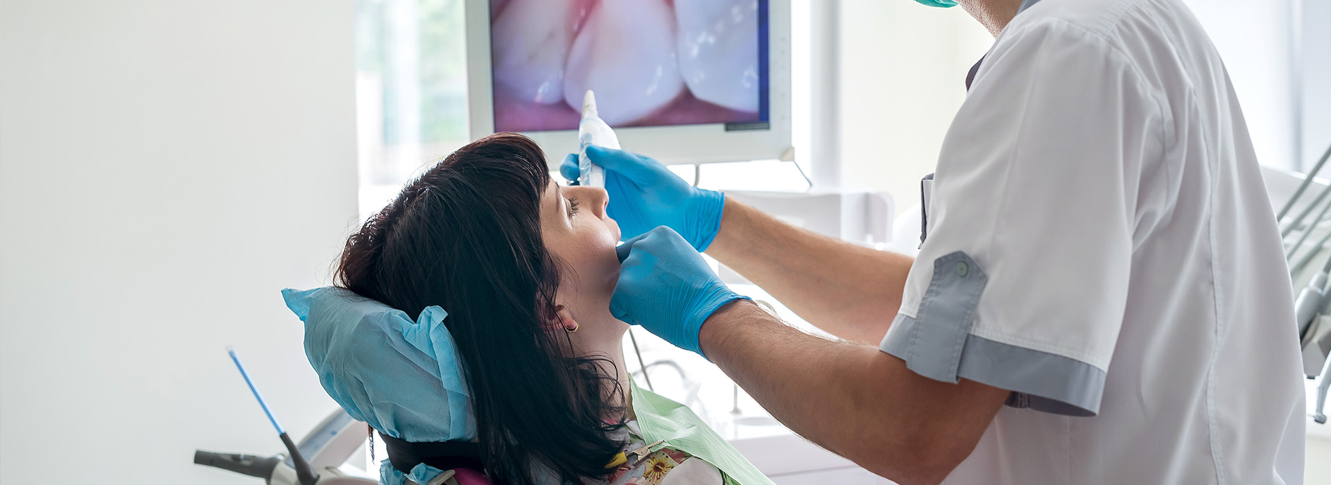 A dental hygienist using a handheld device on a patient s mouth during an oral examination.