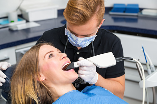 A dentist performing dental work on a patient who is seated in a dental chair.