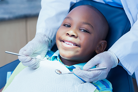 A young boy sitting in a dentist s chair with a smile, receiving dental treatment.